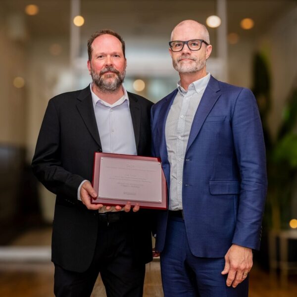 Pierre Koch and Ian Boyle pose holding the 2025 CCE Award Award of Excellence in their Building's Category for the BCIT Tall Timber Student Housing Project