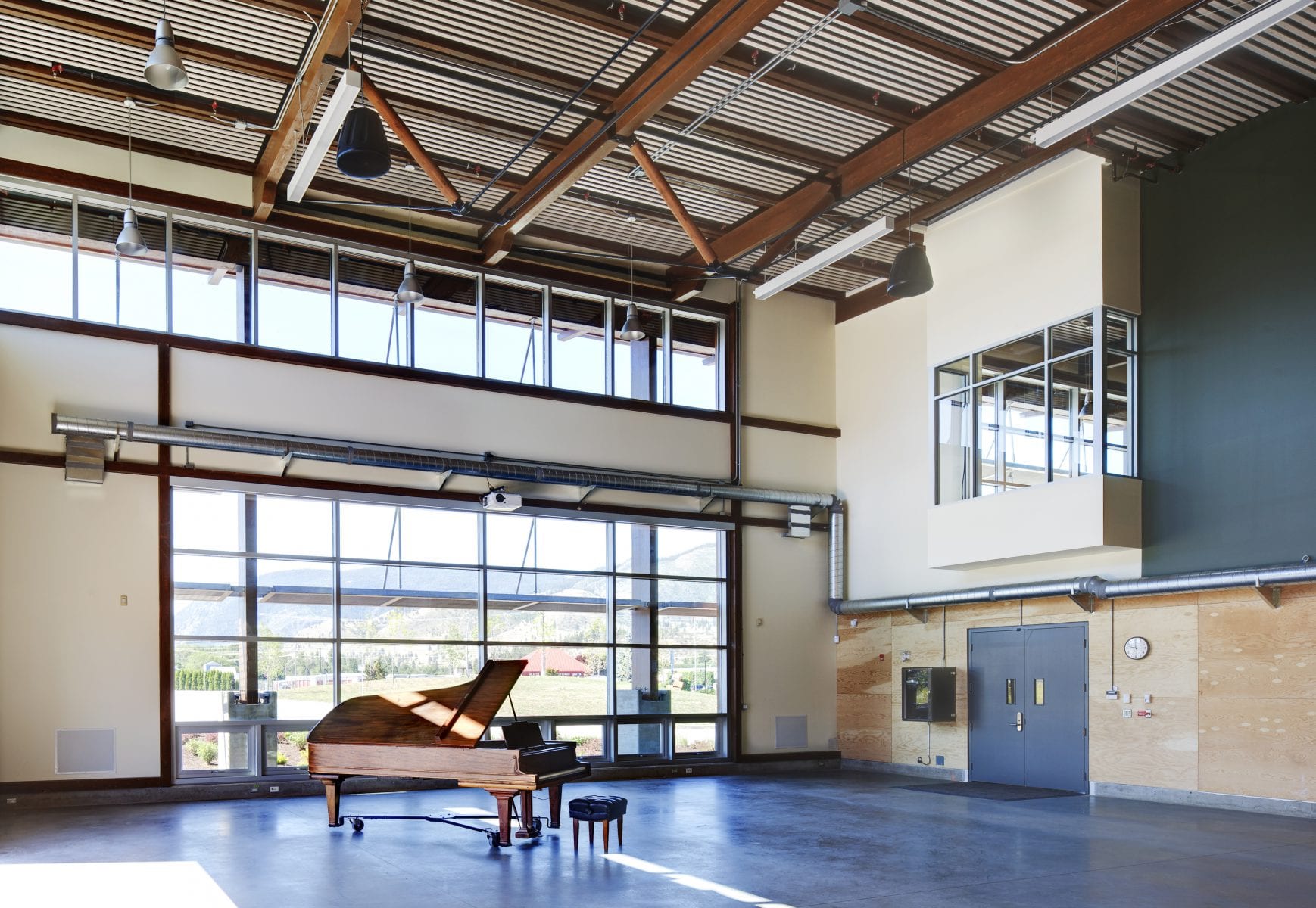 Interior image of assembly room with a piano placed in the middle of the completed Okanagan College Jim Pattison Centre of Excellence.
