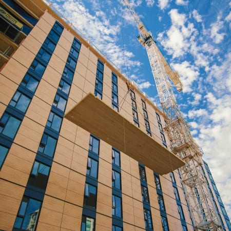 Image shows the installation of mass timber being lifted up by a crane onto the top of the UBC Tallwood House at Brock Commons, which is a 17 storey mass timber project.
