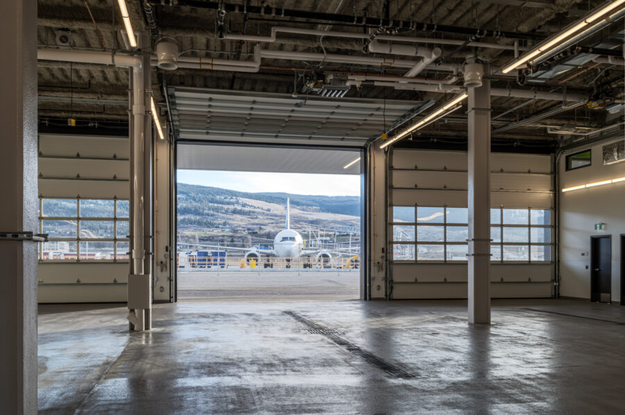 Photo of plane through the bay doors, taken from inside the Kelowna International Airport Operations and Emergency Services Building.