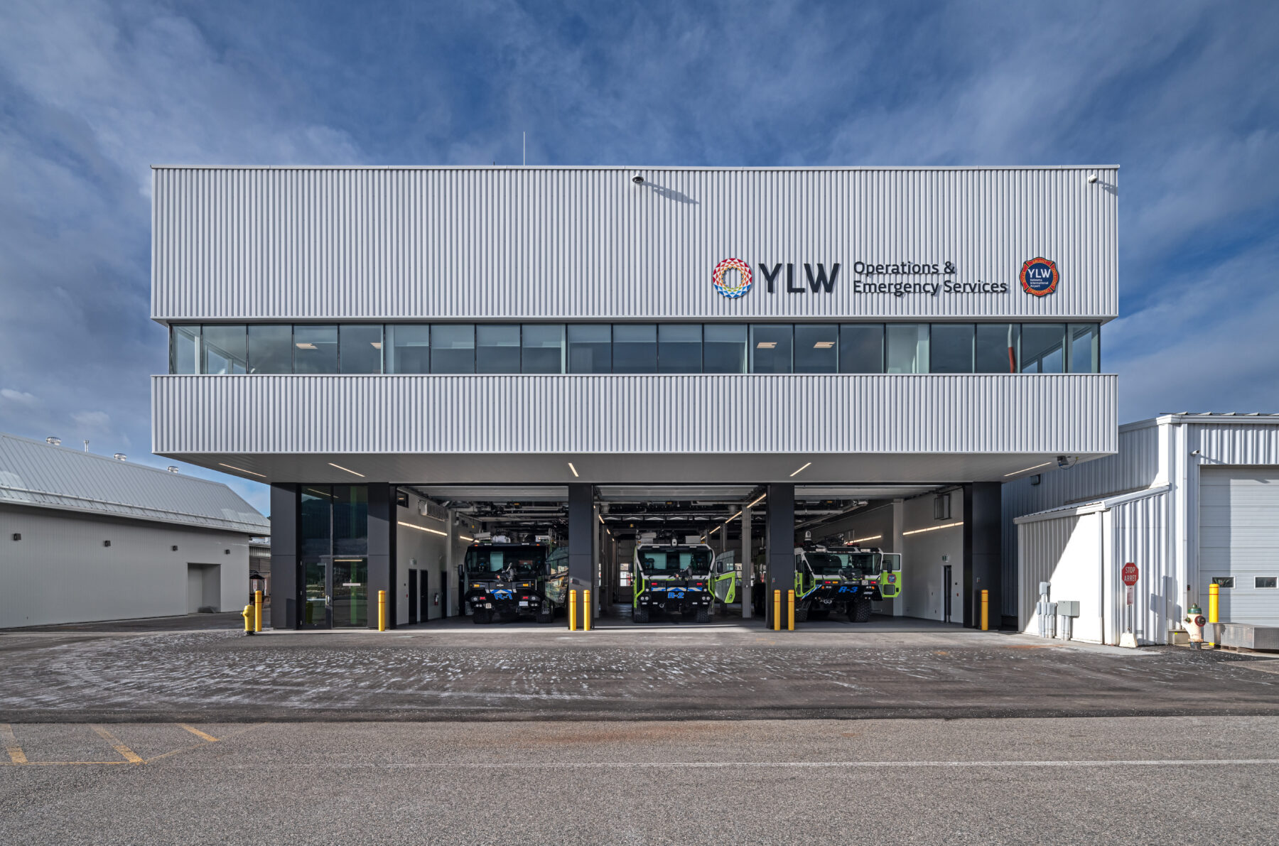 Front view of the Kelowna International Airport Operations and Emergency Services Building with trucks in the loading bay.