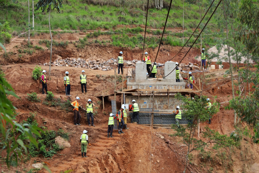 Bridges to Prosperity Ngayake Trail Bridge Build, progress construction image of people working on the suspending of the cables for the bridge