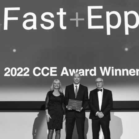 Members of the Fast + Epp team stand on stage as they are presented with an award. Behind the backdrop reads 'Fast + Epp 2022 CCE Award Winner'